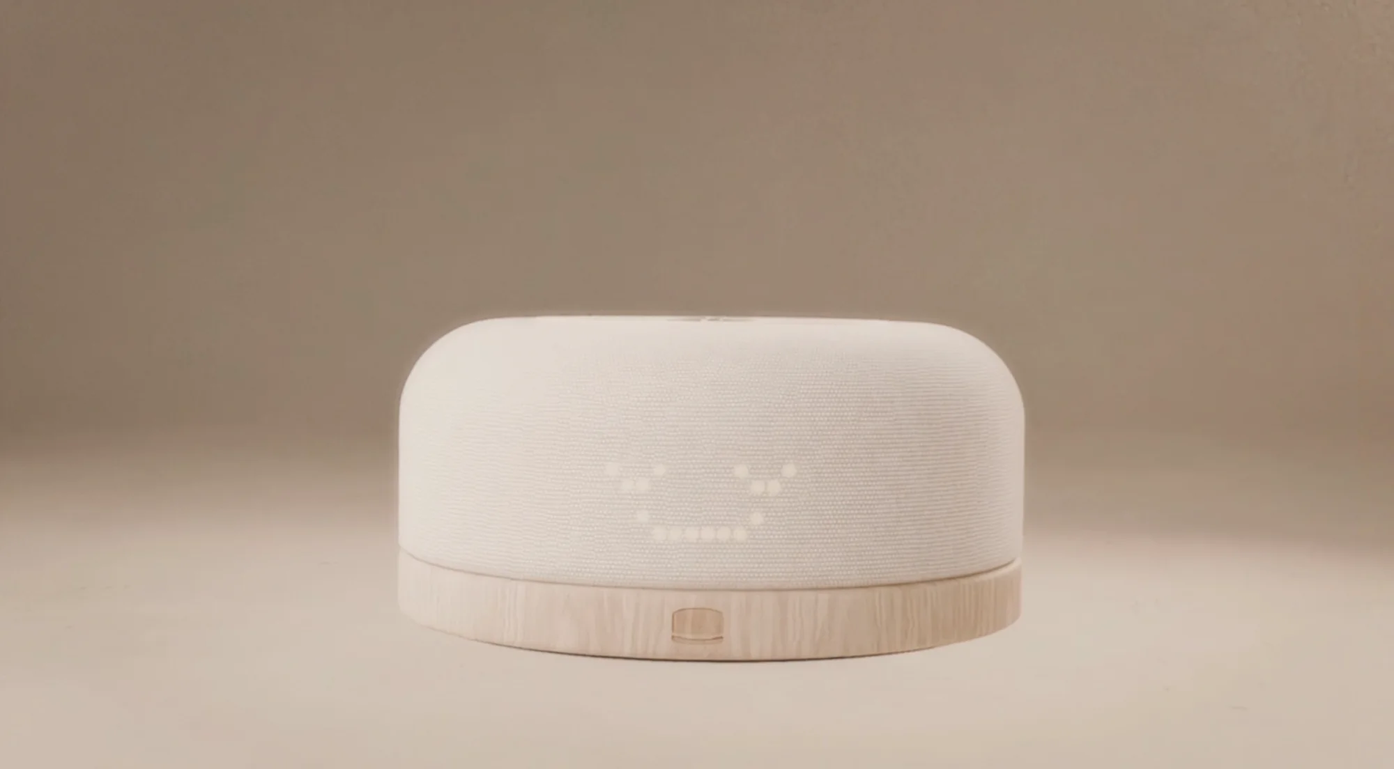 The Hushpup hub on a warm studio backdrop, its LED face smiling through the knit.